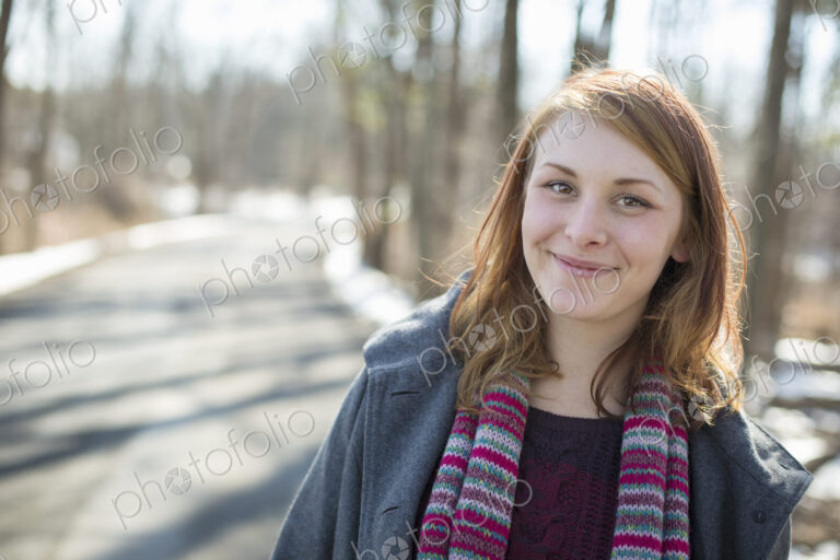 A young woman with a knitted scarf, outdoors on a snowy winter day.