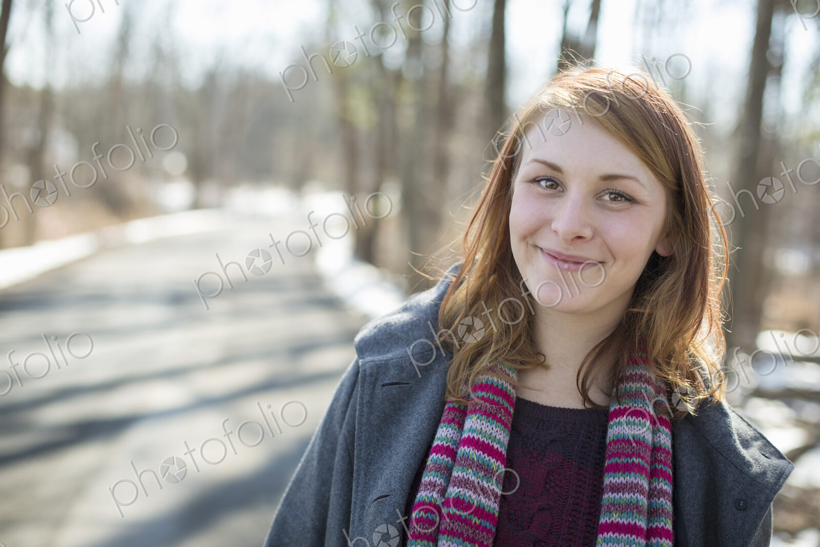 A young woman with a knitted scarf, outdoors on a snowy winter day.