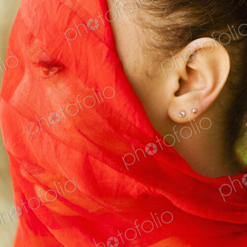 A young woman with a red seethrough sheer veil across her face.
