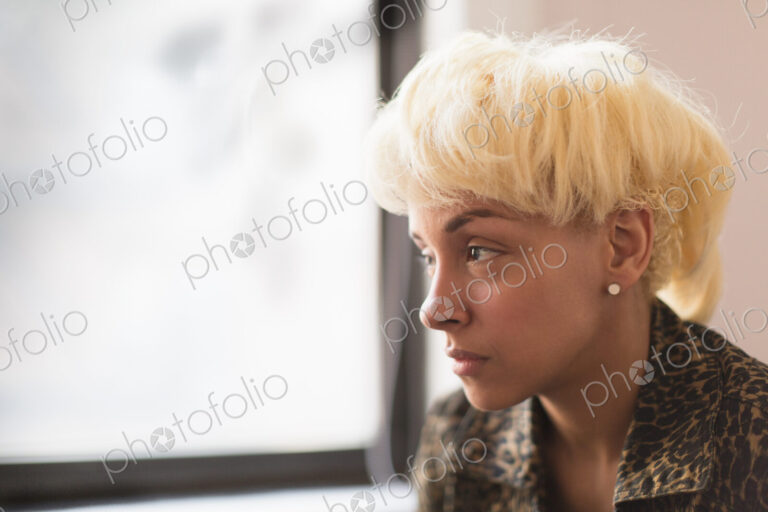 A young woman with blonde hair looking out of the window.