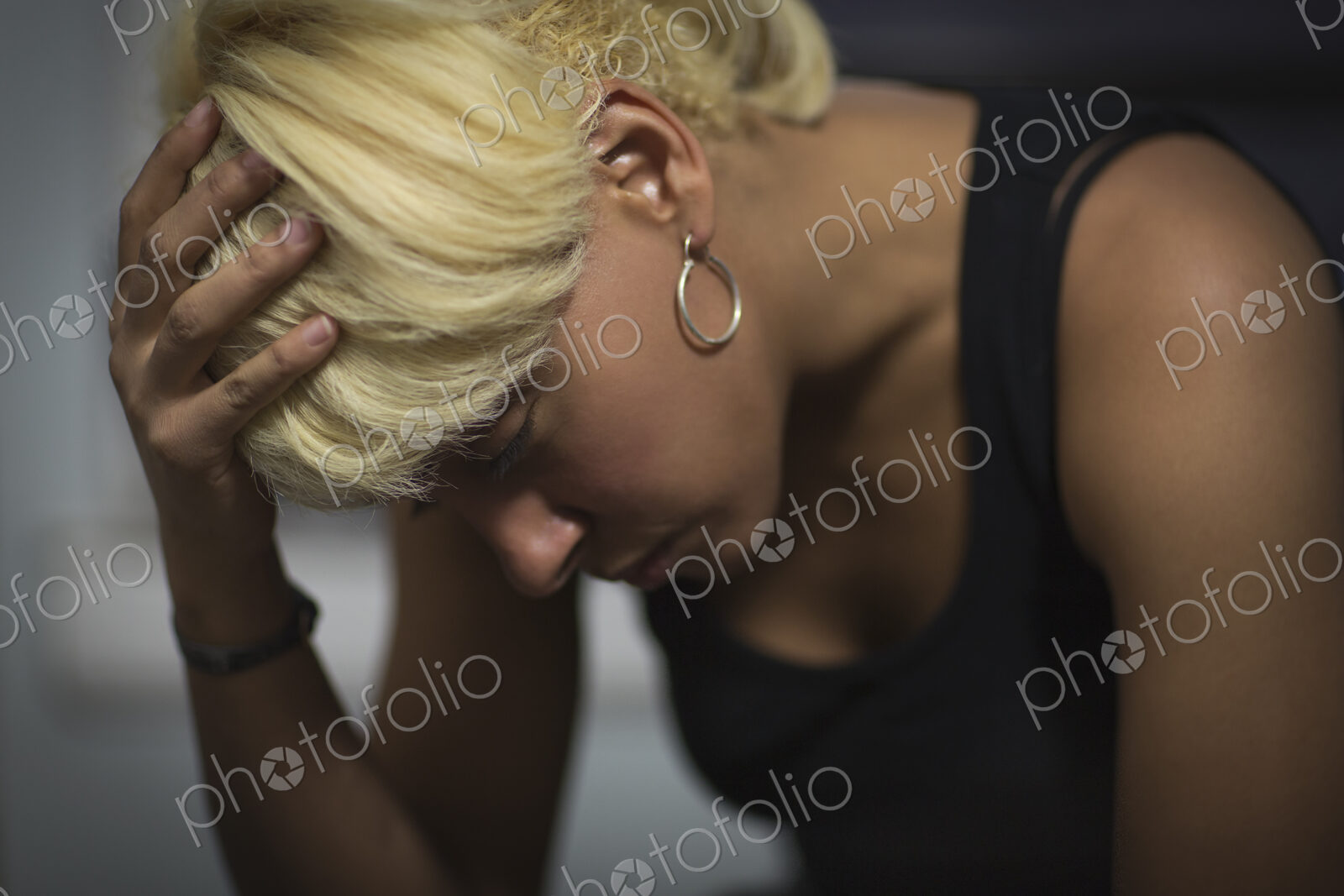 A young woman with blonde hair, with her head in her hands.