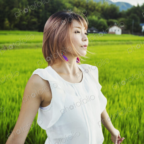 A young woman with hands outstretched, standing in rice paddy fields. A young woman with hands outstretched, standing in rice paddy fields.