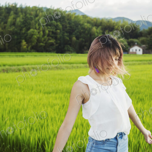 A young woman with hands outstretched, standing in rice paddy fields. A young woman with hands outstretched, standing in rice paddy fields.
