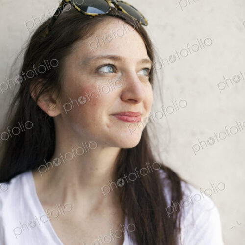 A young woman with long brown hair and sunglasses perched on her head. Wearing a white… A young woman with long brown hair and sunglasses perched on her head. Wearing a white…