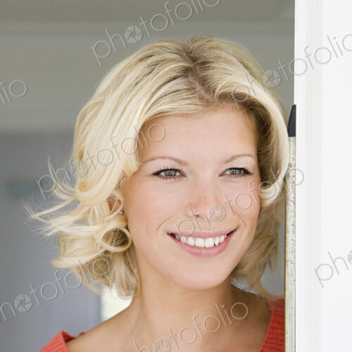A young women with blonde hair smiling in a doorway. A young women with blonde hair smiling in a doorway.