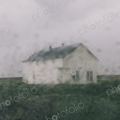Abandoned farmhouse in a rainstorm, seen through a wet window. Blurred image.