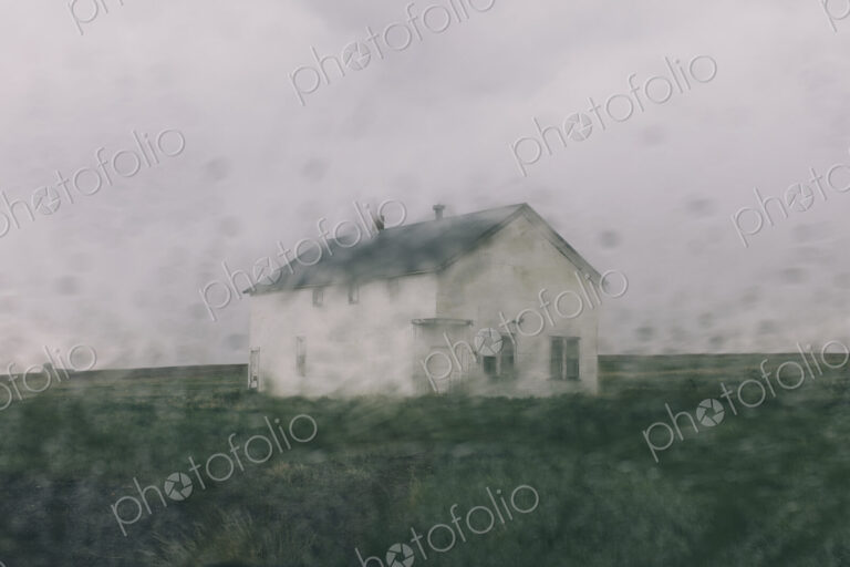 Abandoned farmhouse in a rainstorm, seen through a wet window. Blurred image.