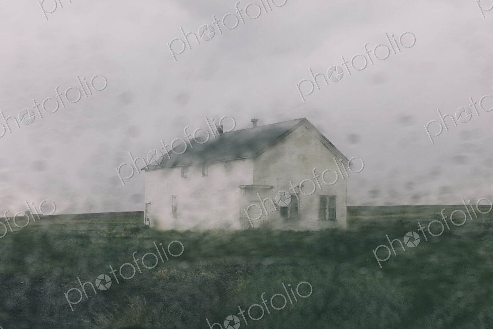 Abandoned farmhouse in a rainstorm, seen through a wet window. Blurred image.