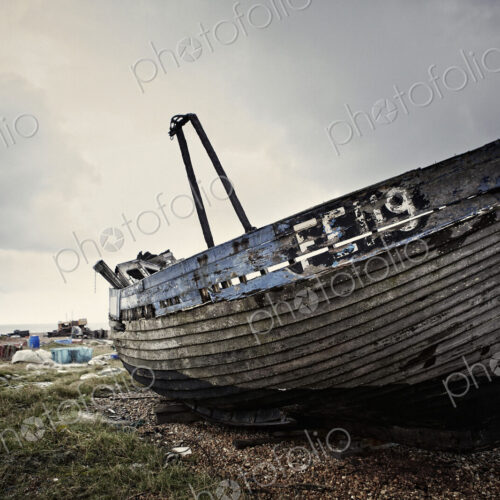 Abandoned wooden boat lying on a shingle beach.