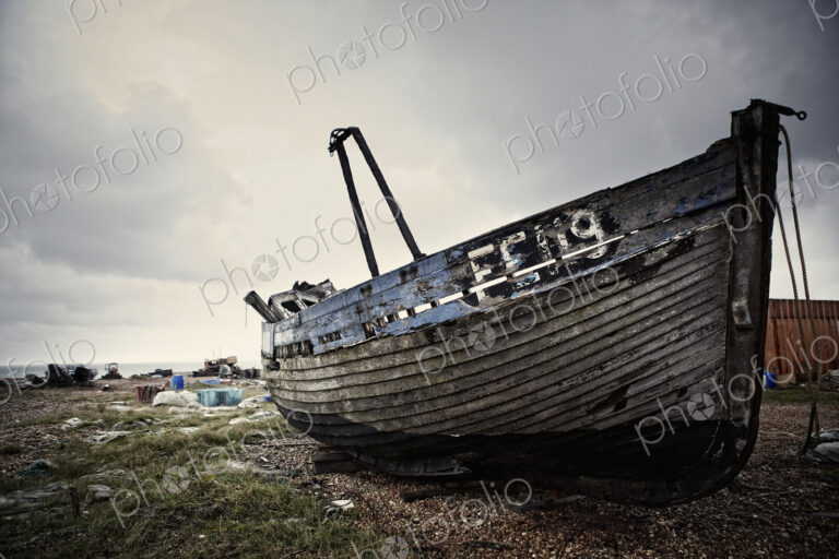 Abandoned wooden boat lying on a shingle beach.