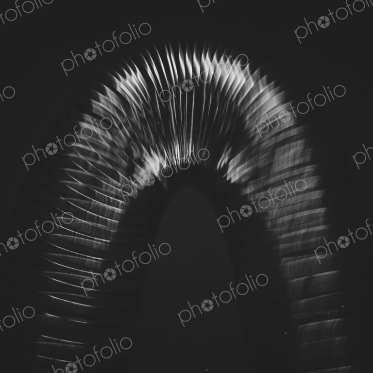 Abstract of metal coiled slinky, length of fine wire wound around and stretched,…