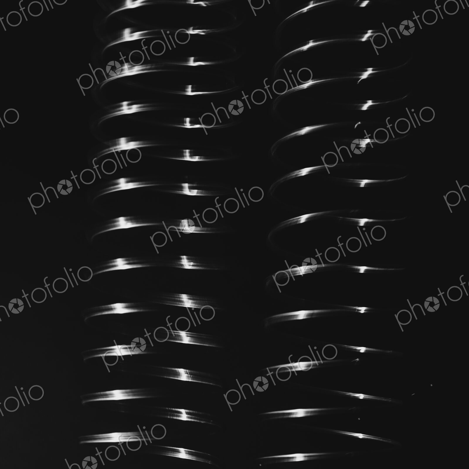 Abstract pattern, light shining on a length of fine wire wound around and stretched,…
