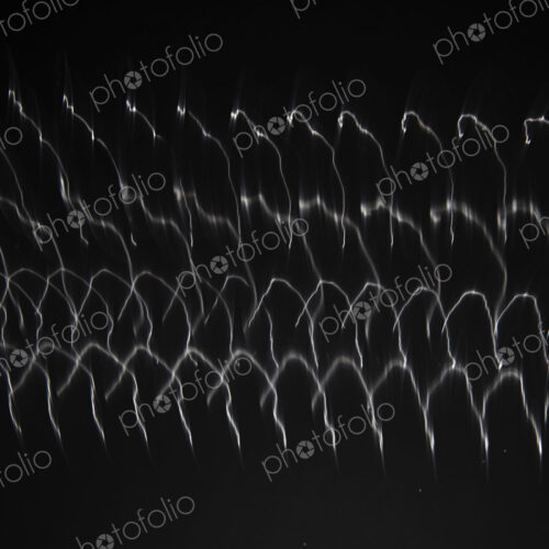 Abstract pattern of light shining on coiled metal, length of fine wire wound around…
