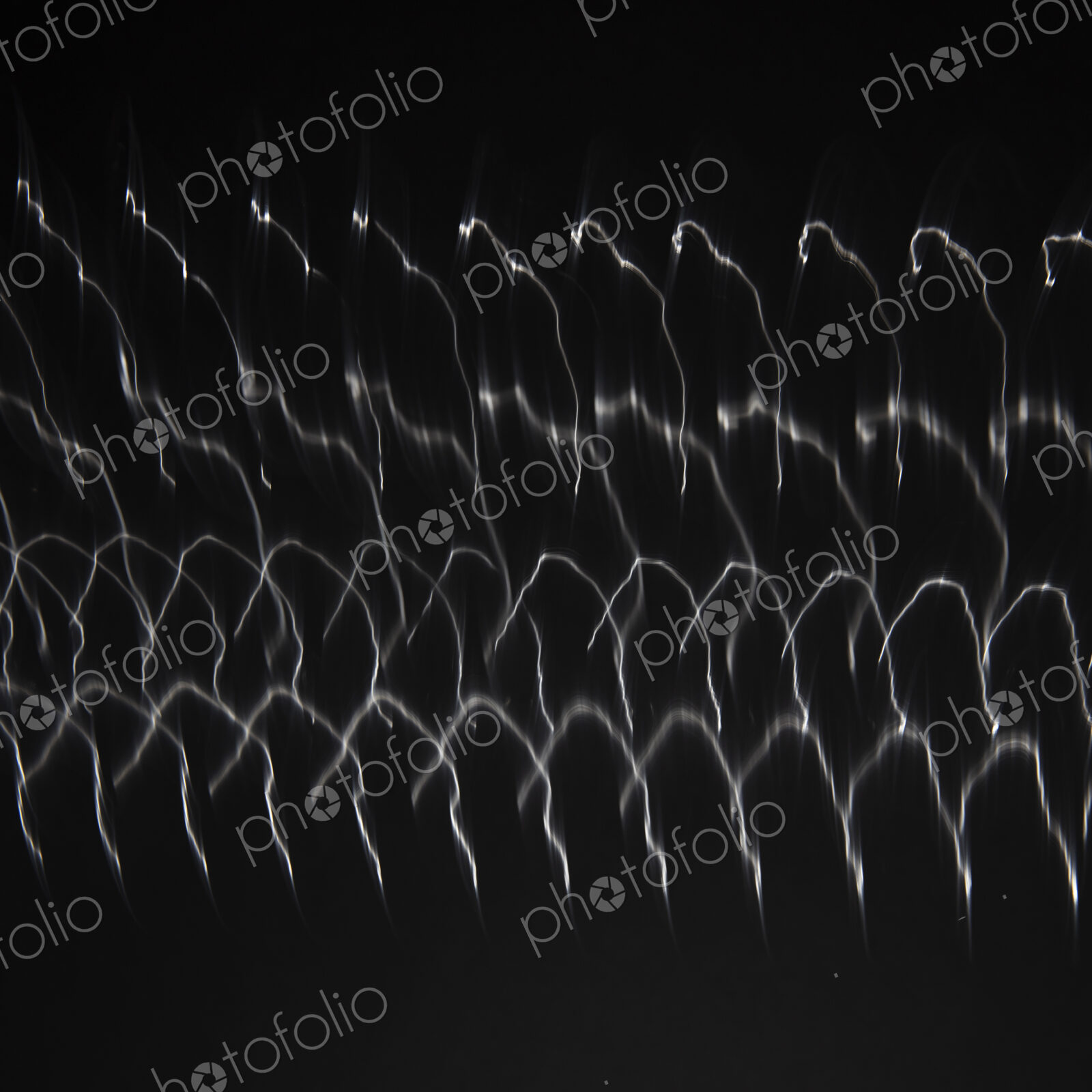 Abstract pattern of light shining on coiled metal, length of fine wire wound around…