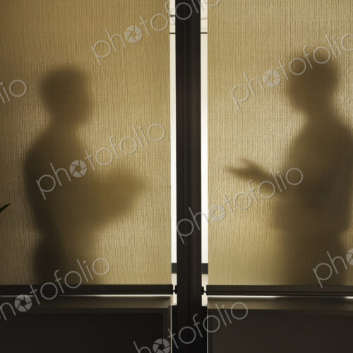 Abstract shadows of two businessman in a meeting behind a window.