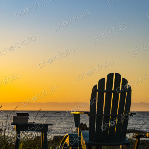 Adirondack chairs on the beach at sunset, an orange sunset glow on the horizon. Adirondack chairs on the beach at sunset, an orange sunset glow on the horizon.