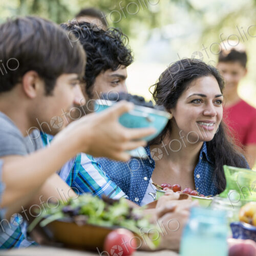 Adults and children around a table at a party in a garden. Adults and children around a table at a party in a garden.