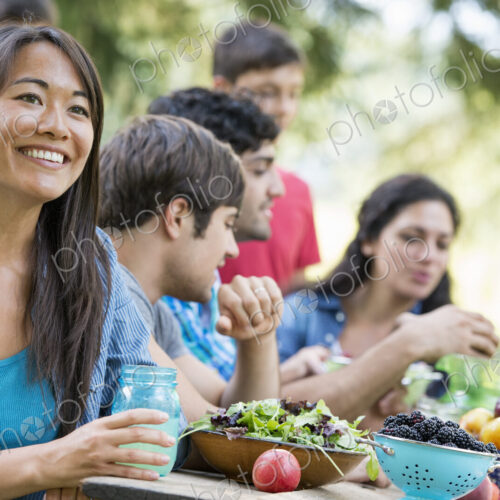 Adults and children around a table at a party in a garden. Adults and children around a table at a party in a garden.