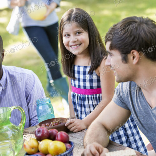 Adults and children around a table at a party in a garden.