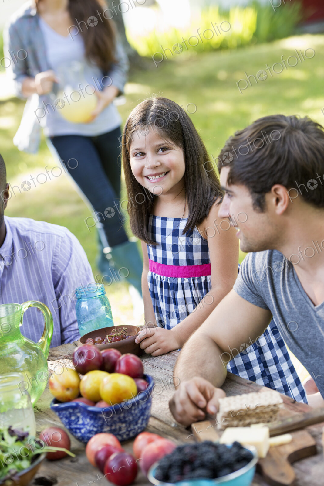 Adults and children around a table at a party in a garden.