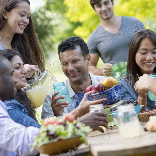 Adults and children around a table in a garden. Adults and children around a table in a garden.