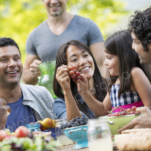 Adults and children around a table in a garden. Adults and children around a table in a garden.