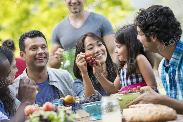 Adults and children around a table in a garden.