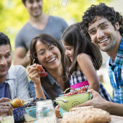 Adults and children around a table in a garden. Adults and children around a table in a garden.