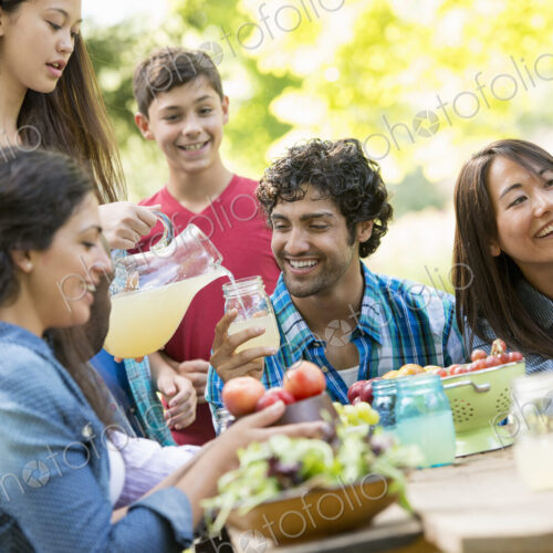 Adults and children around a table in a garden. Adults and children around a table in a garden.