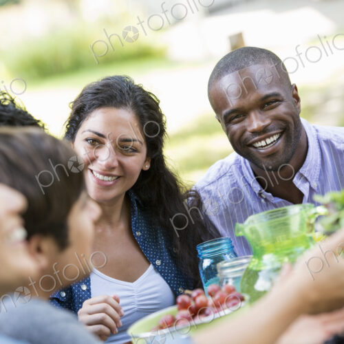 Adults and children around a table in a garden. Adults and children around a table in a garden.