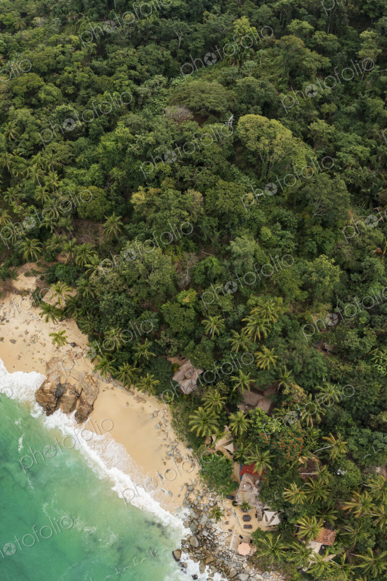 Aerial View of Casitas Marika beach, small beach huts and a thick cover of palm trees…