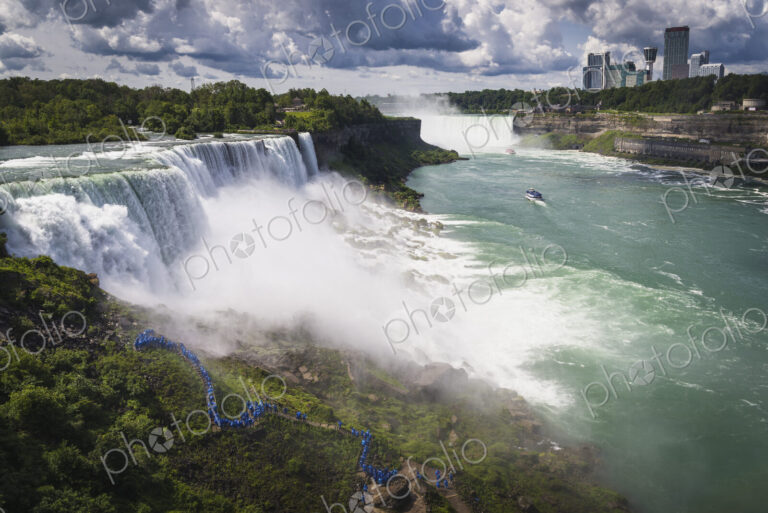 Aerial view of Niagara Falls with skyscrapers beyond.