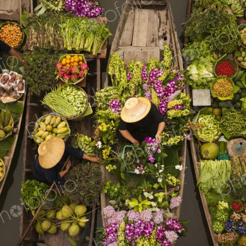 Aerial view of a floating market on a canal in Bangkok, local boats laden with fresh…