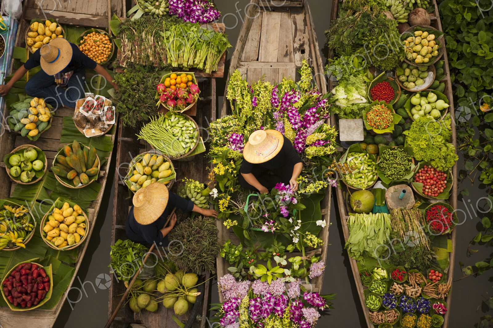 Aerial view of a floating market on a canal in Bangkok, local boats laden with fresh…