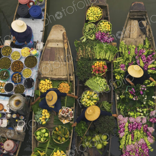 Aerial view of a floating market on a canal in Bangkok, local boats laden with fresh…