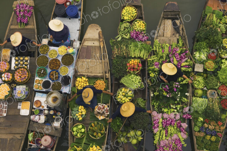 Aerial view of a floating market on a canal in Bangkok, local boats laden with fresh…
