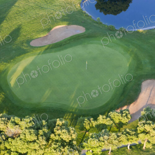 Aerial view of a golf course with lush green lawn, trees and and bunkers. Aerial view of a golf course with lush green lawn, trees and and bunkers.