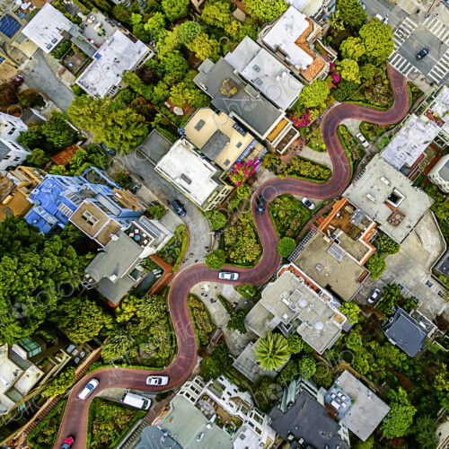 Aerial view of a residential city area, with road descending a hillside with eight…
