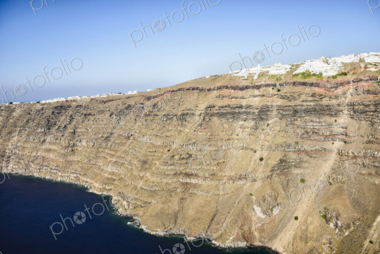 Aerial view of a town at the top of a sheer cliff on the island of Egeo, whitewashed…
