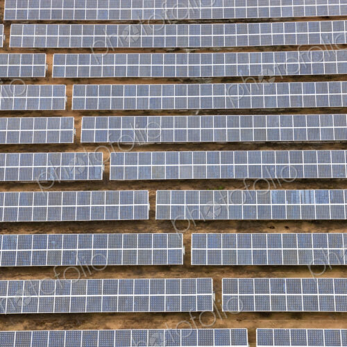 Aerial view of long rows of solar panels in the desert.