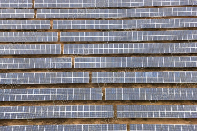 Aerial view of long rows of solar panels in the desert.