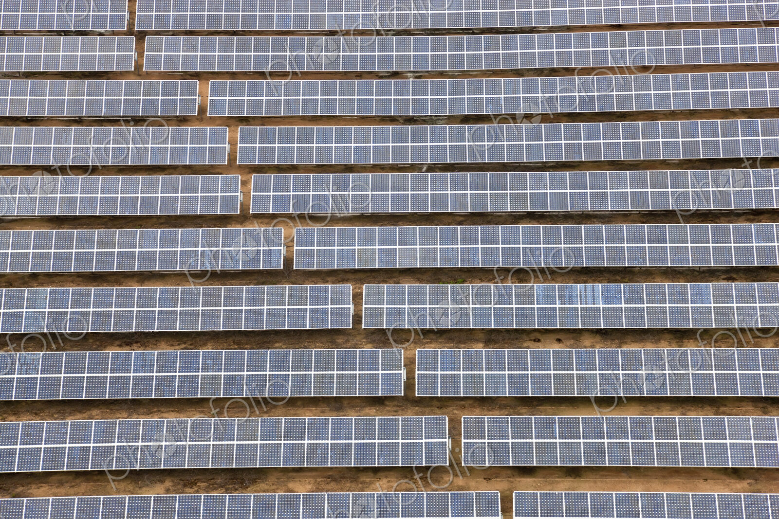 Aerial view of long rows of solar panels in the desert.