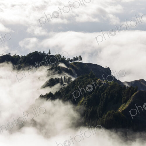 Aerial view of lush mountains on an island, surrounded by clouds. Aerial view of lush mountains on an island, surrounded by clouds.