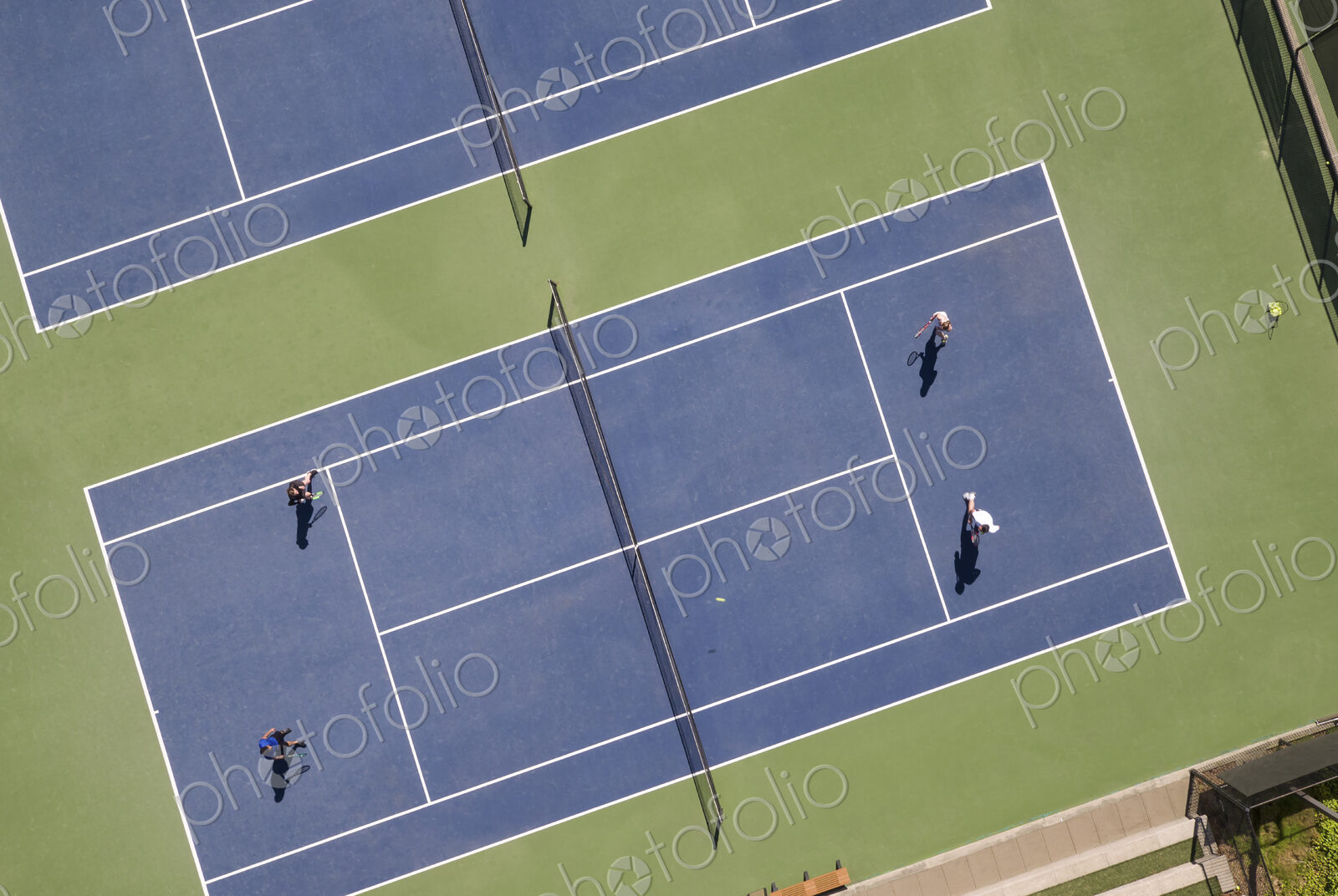 Aerial view of tennis court and people playing tennis.