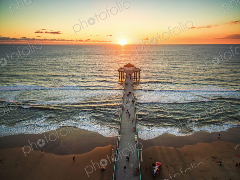 Aerial view of the Manhattan Beach Pier and waves breaking on the shore.