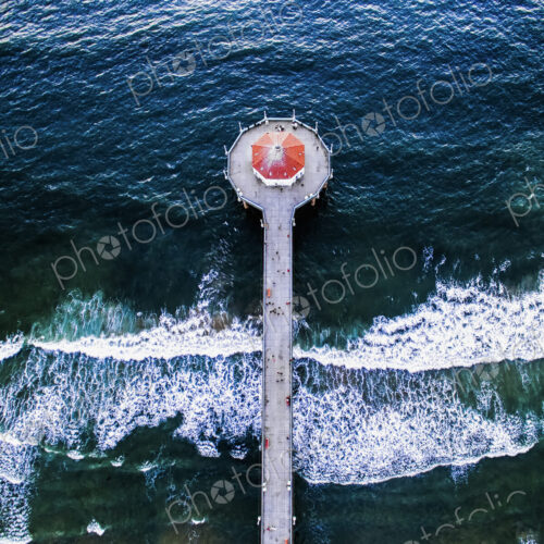 Aerial view of the Manhattan Beach Pier and waves breaking on the shore.