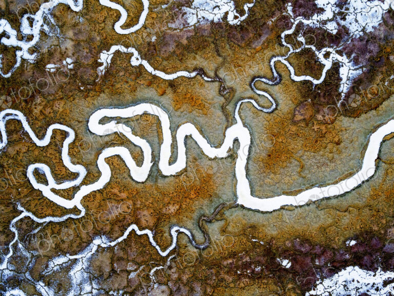 Aerial view of the landscape, meandering water channels and the salt pans with white…