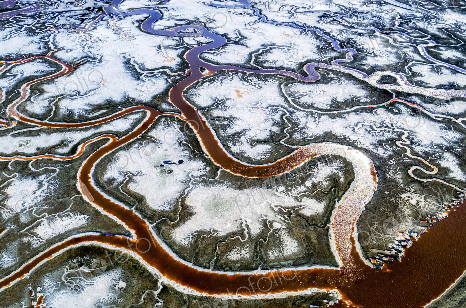Aerial view of the landscape, meandering water channels and the salt pans with white…