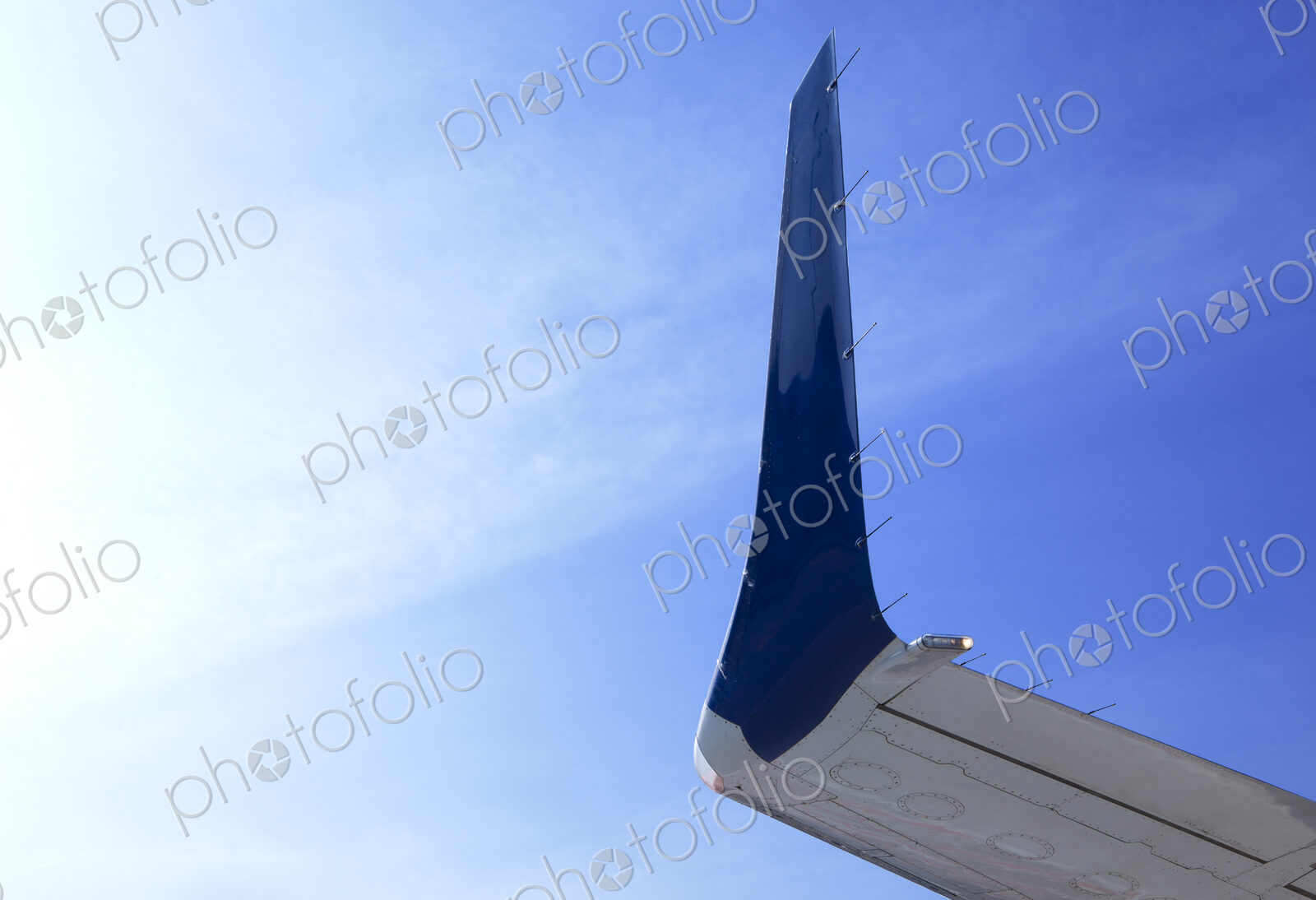Aircraft wingtip, low angle view, against blue sky.