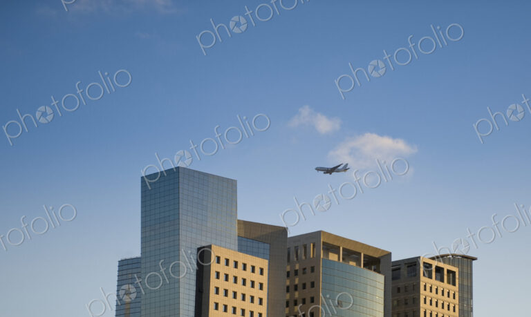 Airplane Flying Over Office Buildings